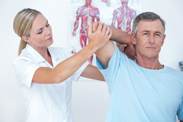 Female physiotherapist raising a mans elbow
